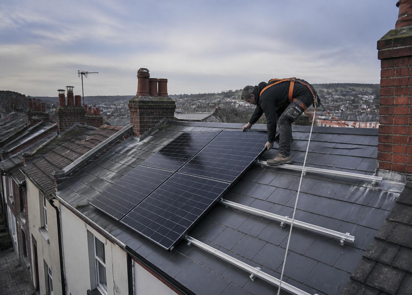 Installer fitting solar panels to a slate roof above Bristol